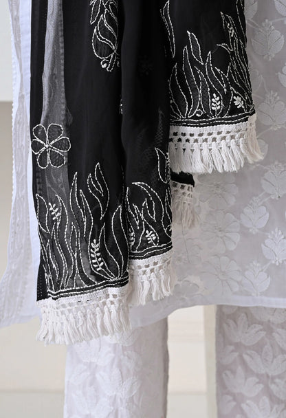 Black and white embroidered fabric dupatta with tassels on a textured background