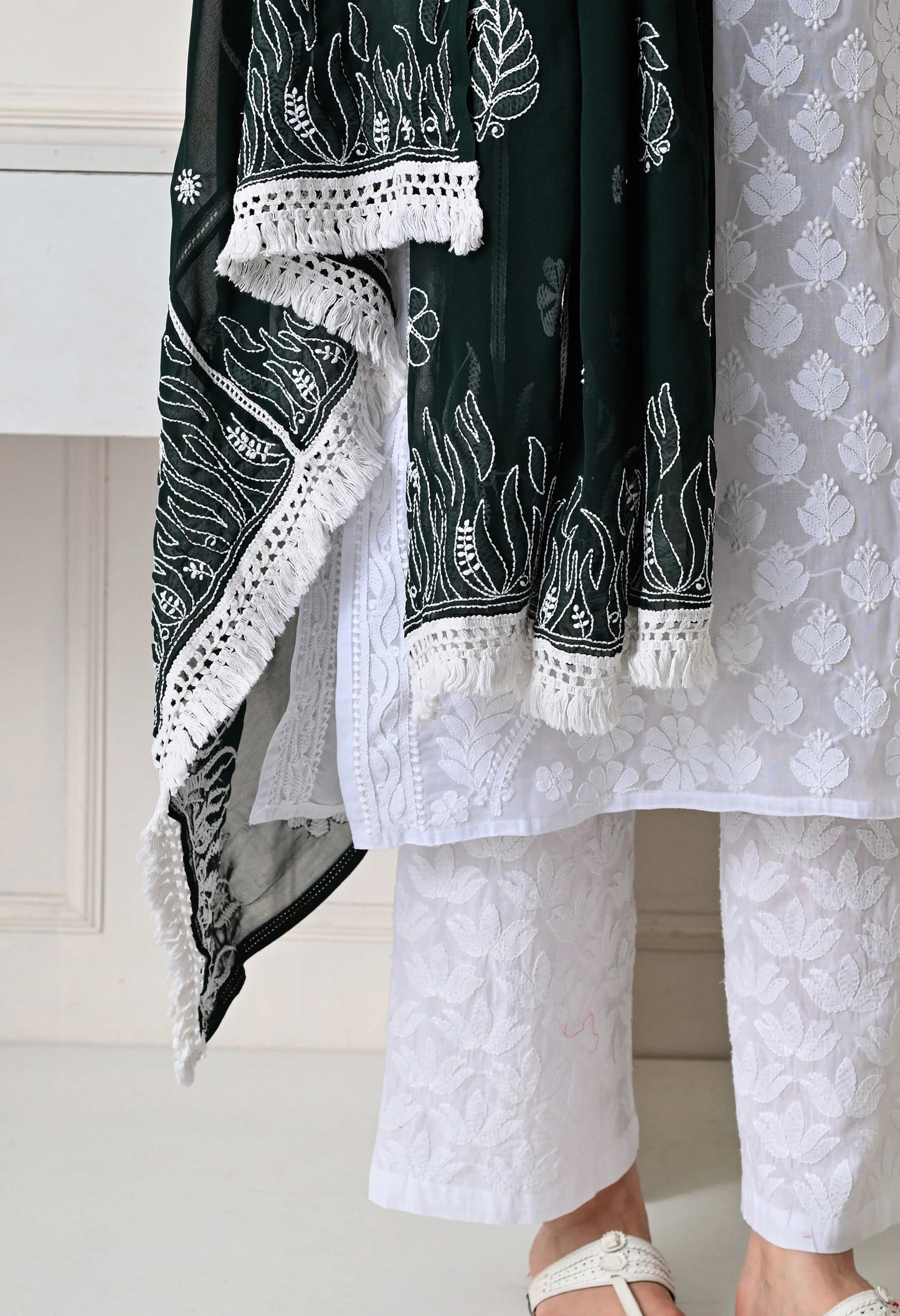 Black and white embroidered traditional outfit with white pants on a neutral background