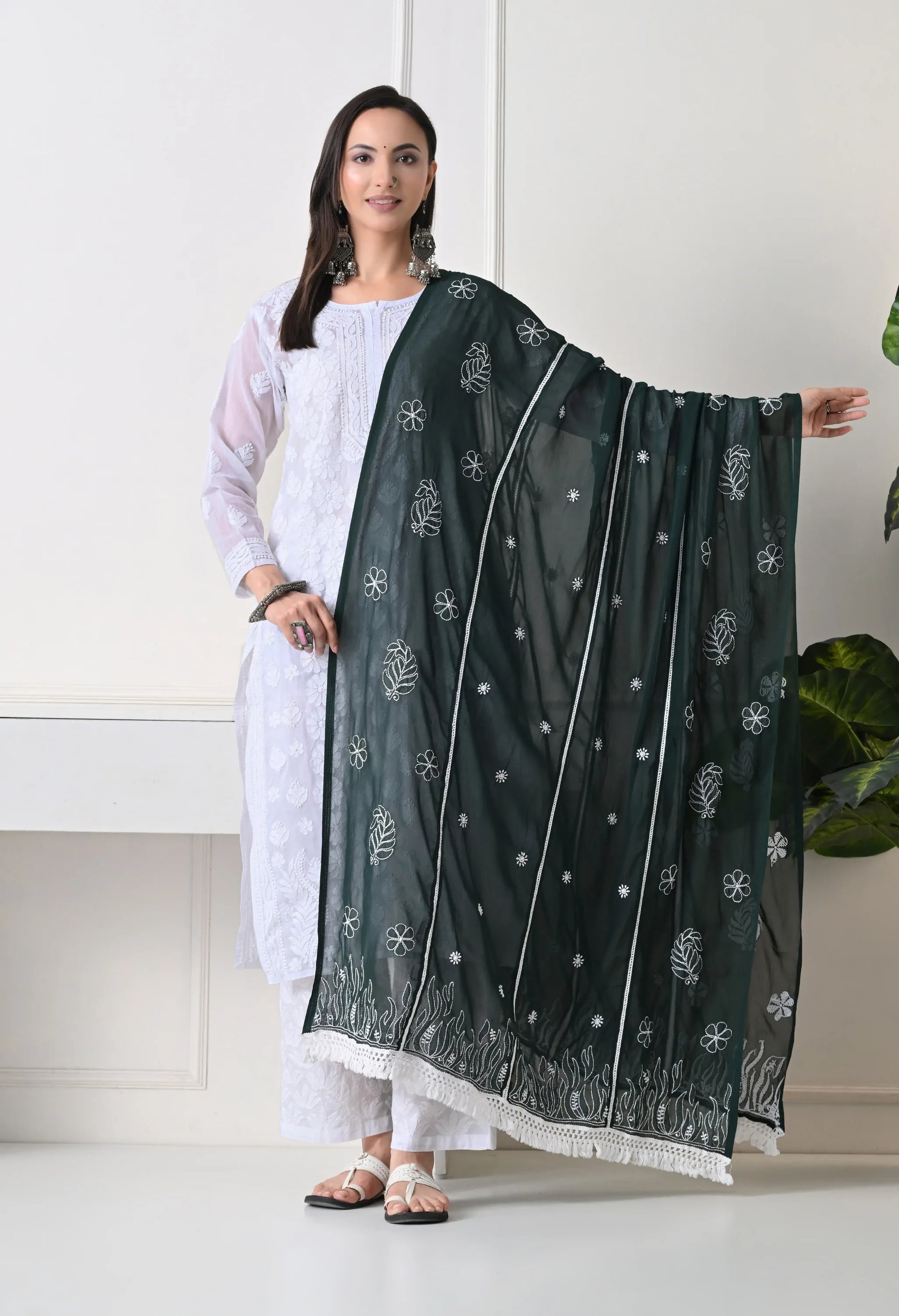Woman holding a bottle green dupatta with white patterns in a minimal indoor setting