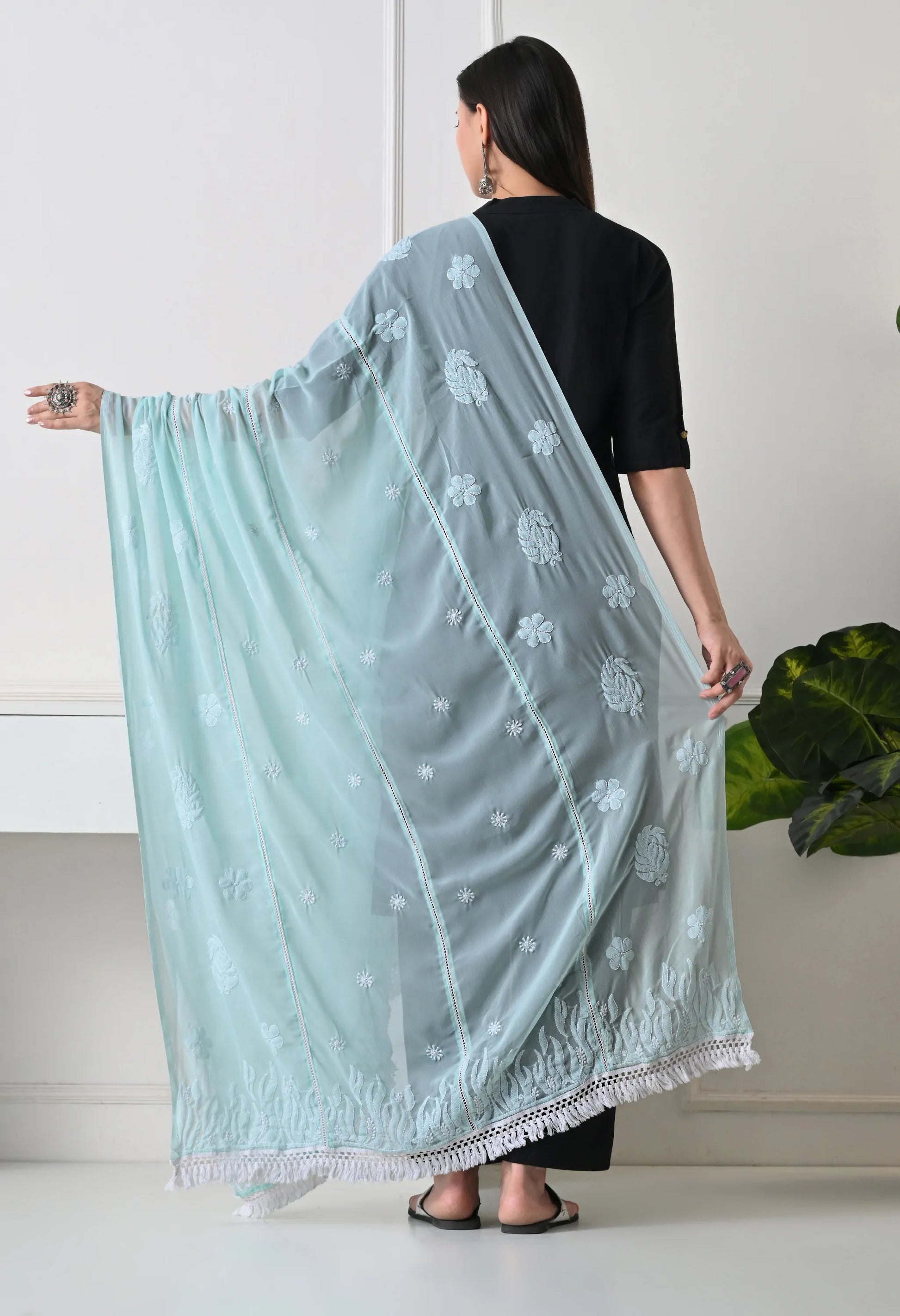 Woman holding a l embroidered mint green dupatta against a white background