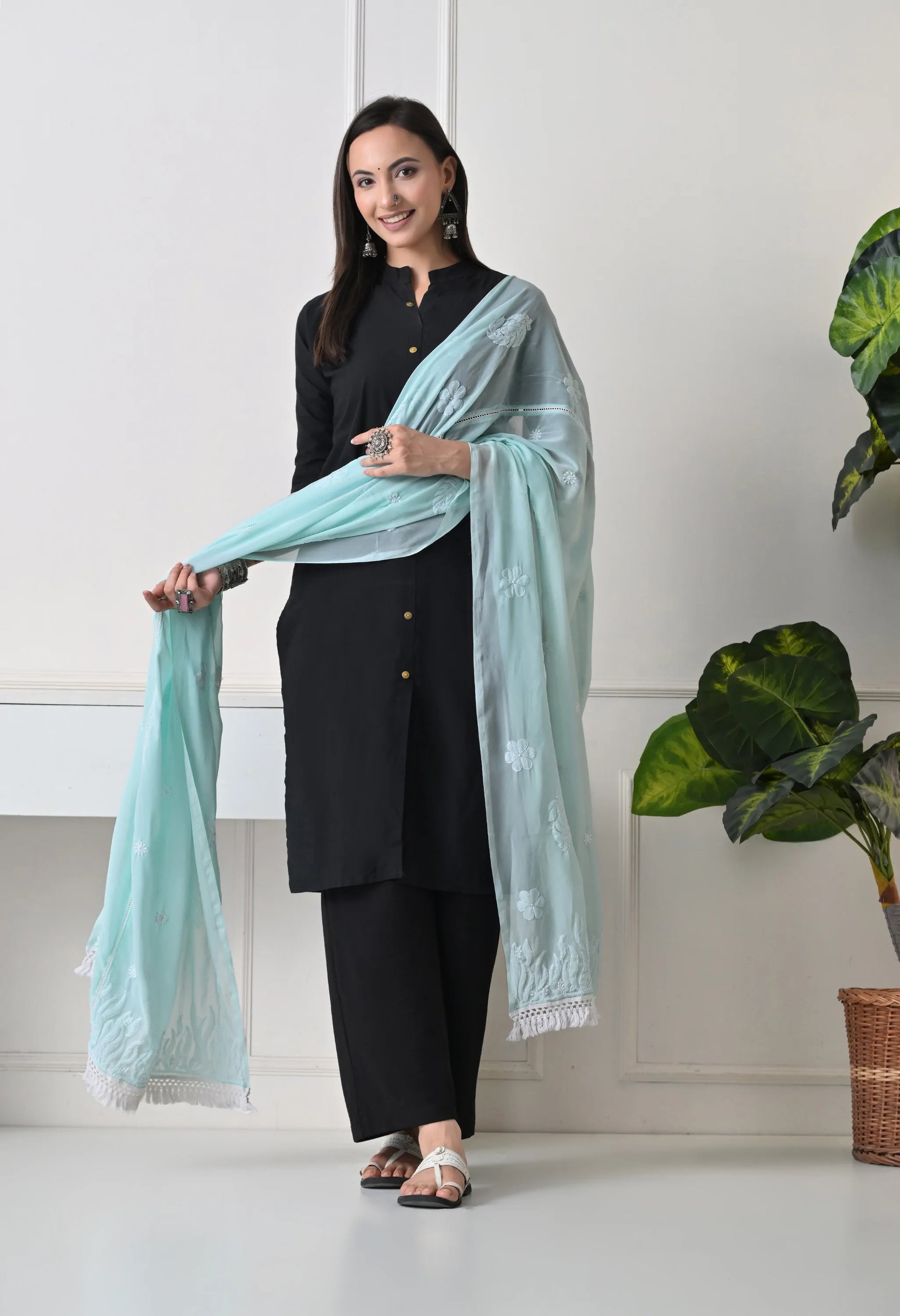 Woman holding a light blue scarf/dupatta in a minimal indoor setting