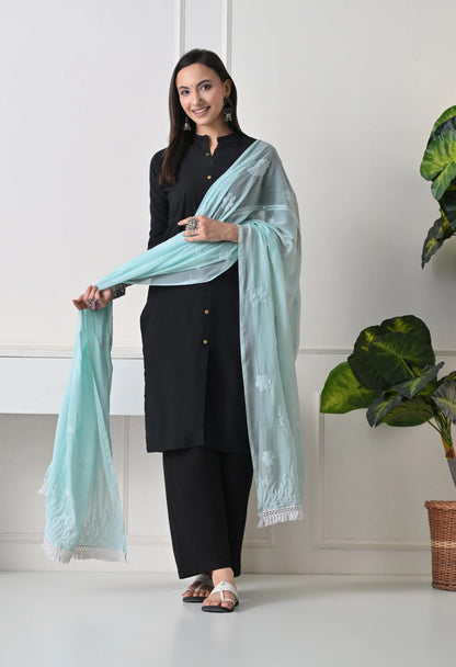 Woman holding a light blue scarf/dupatta in a minimal indoor setting