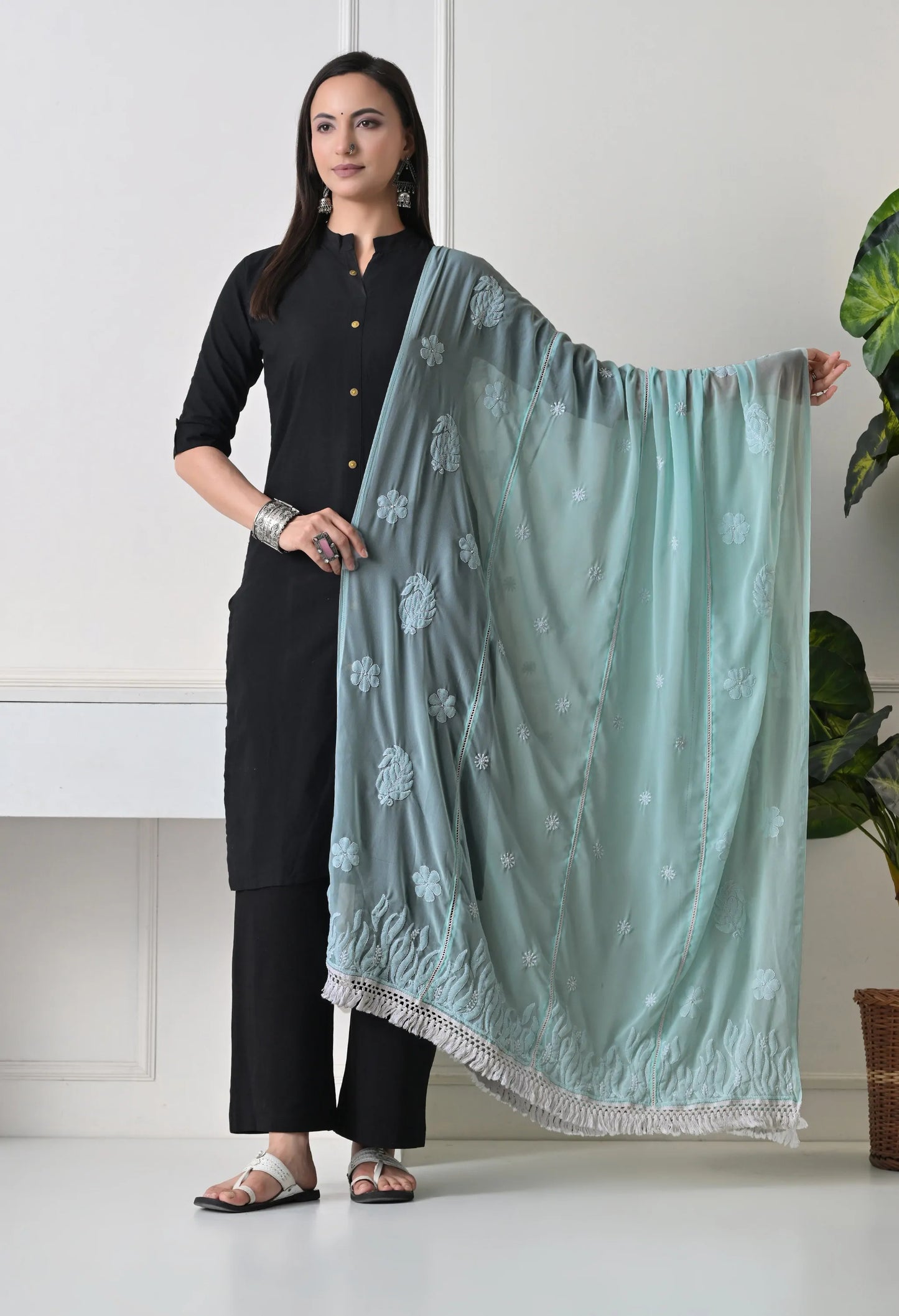 Woman holding a mint green dupatta with white patterns in a minimal indoor setting