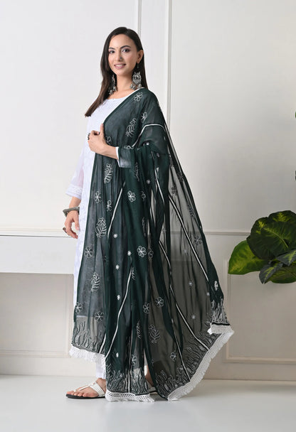 Woman wearing a bottle green saree with white patterns on a white background