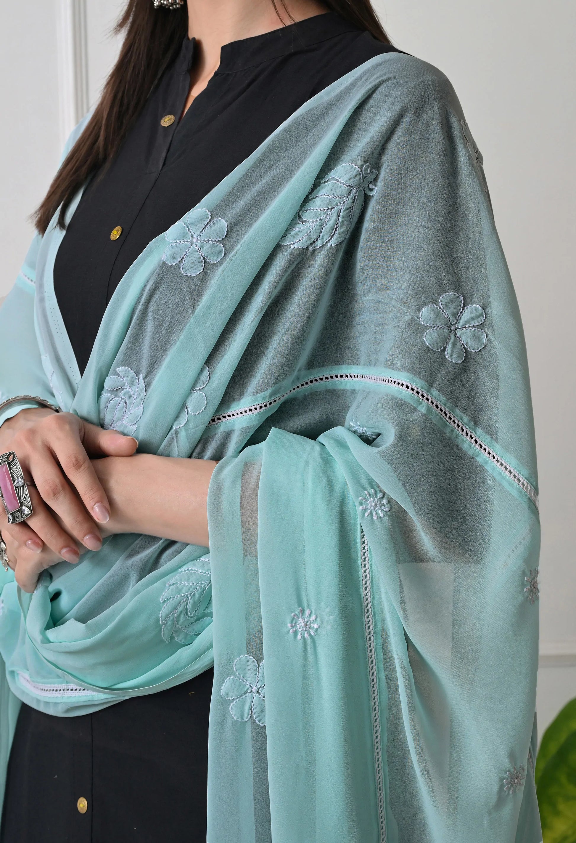 Woman wearing a mint green embroidered dupatta over a black outfit.