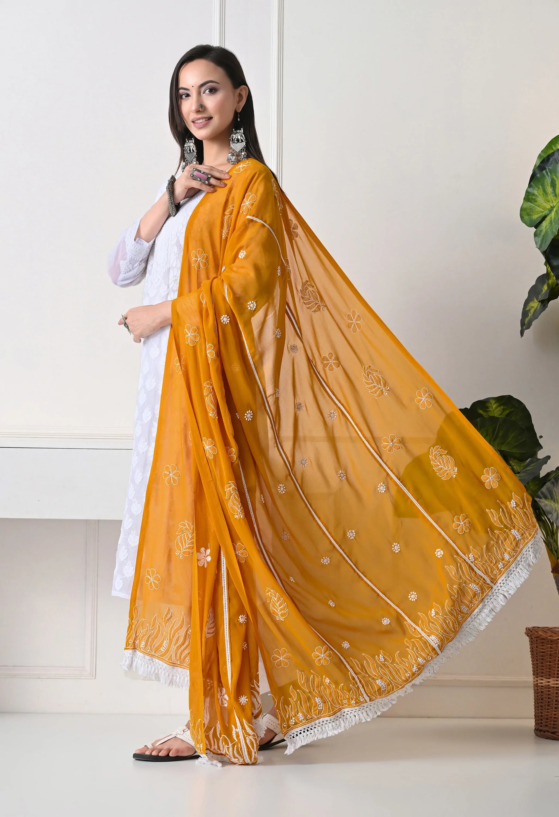 Woman wearing a mustard yellow dupatta with white patterns on a white background