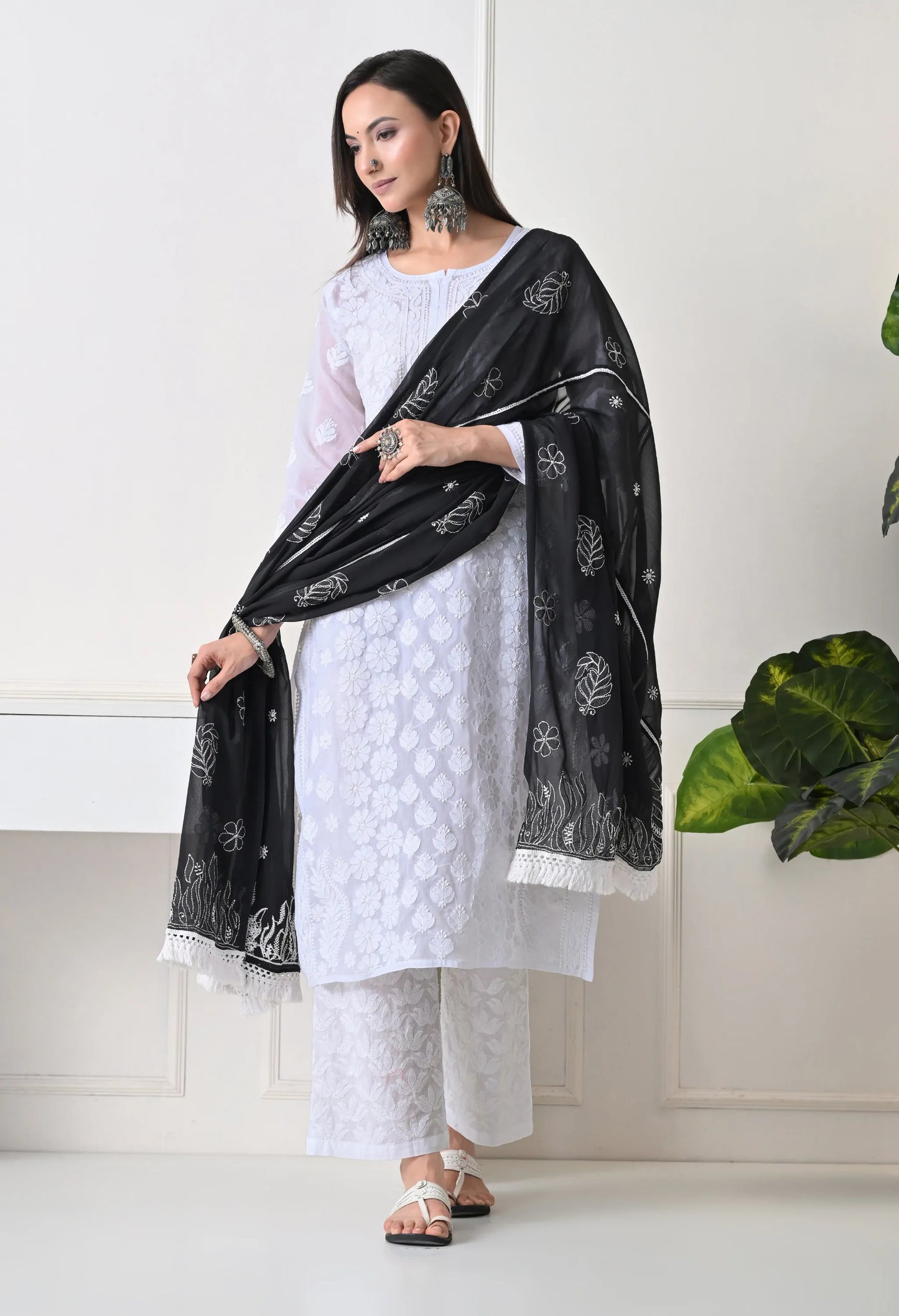 Woman wearing a white outfit with a black dupatta in a minimalistic setting
