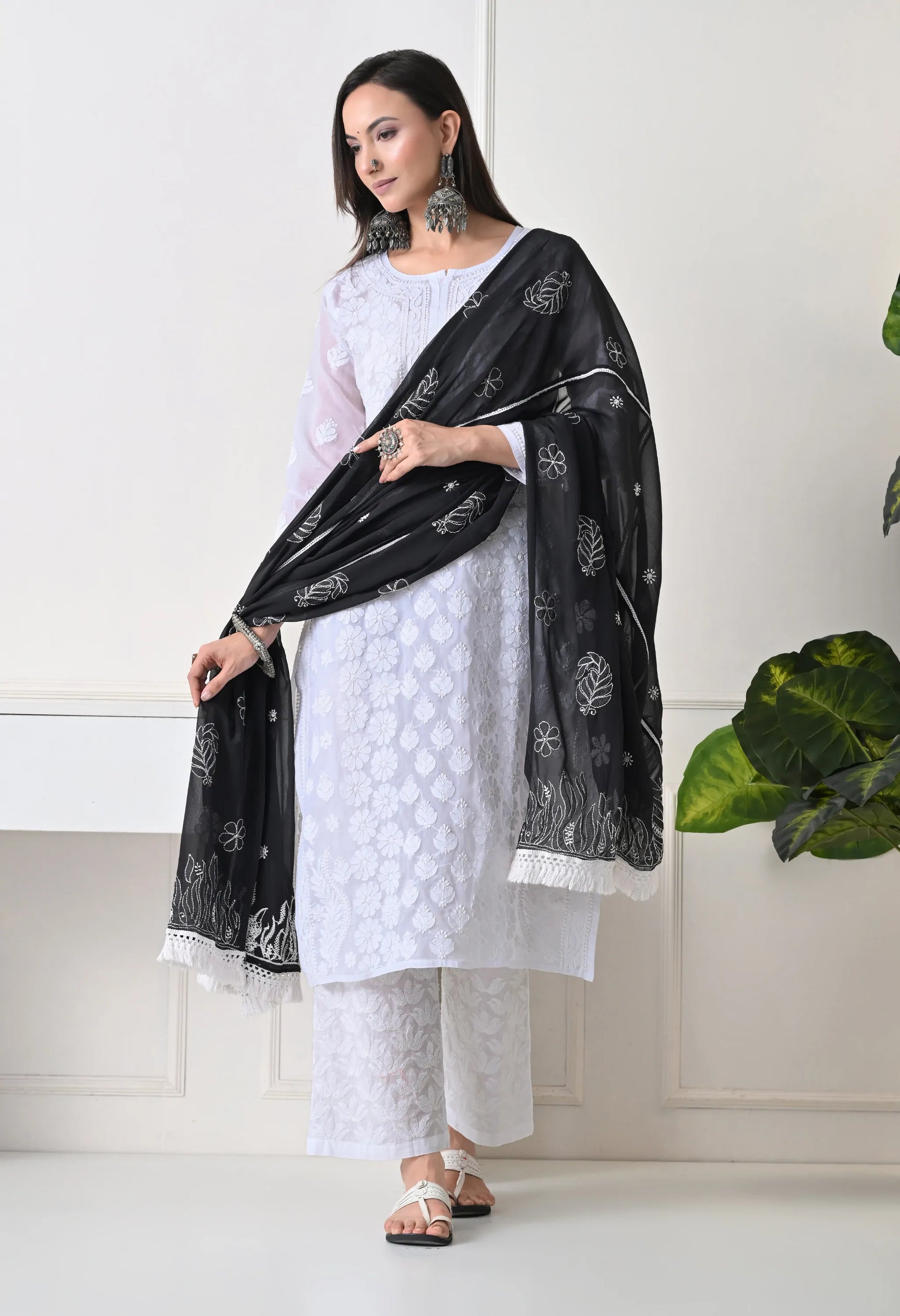 Woman wearing a white outfit with a black dupatta in a minimalistic setting