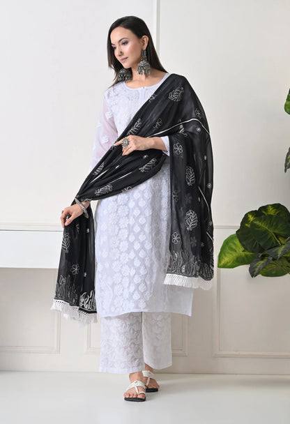 Woman wearing a white outfit with a black dupatta in a minimalistic setting