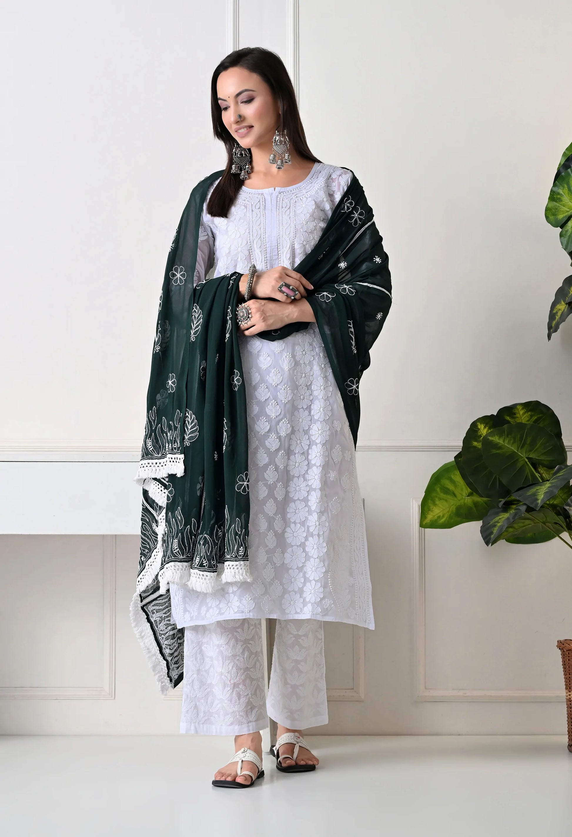 Woman wearing a white outfit with a bottle green dupatta in a minimalistic setting