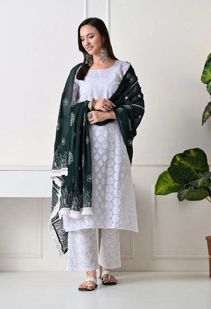 Woman wearing a white outfit with a bottle green dupatta in a minimalistic setting