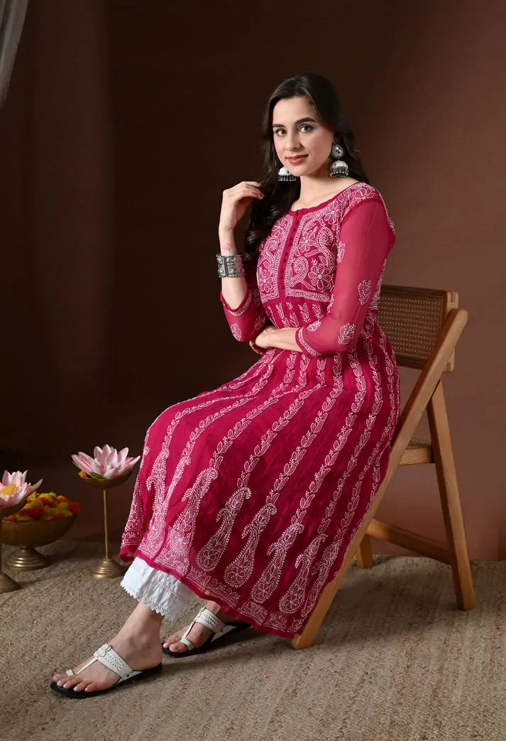 Seated model wearing pink floral anarkali kurta set with white pants